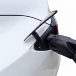 Пистолет станции CCS2 подключён через адаптер к зарядному порту белой Tesla Model 3