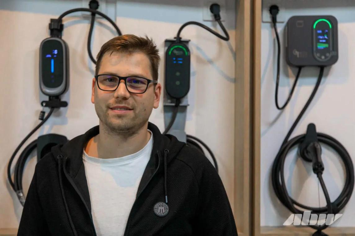 Дмитрий, директор GreenLight, на фоне зарядных устройств в шоуруме