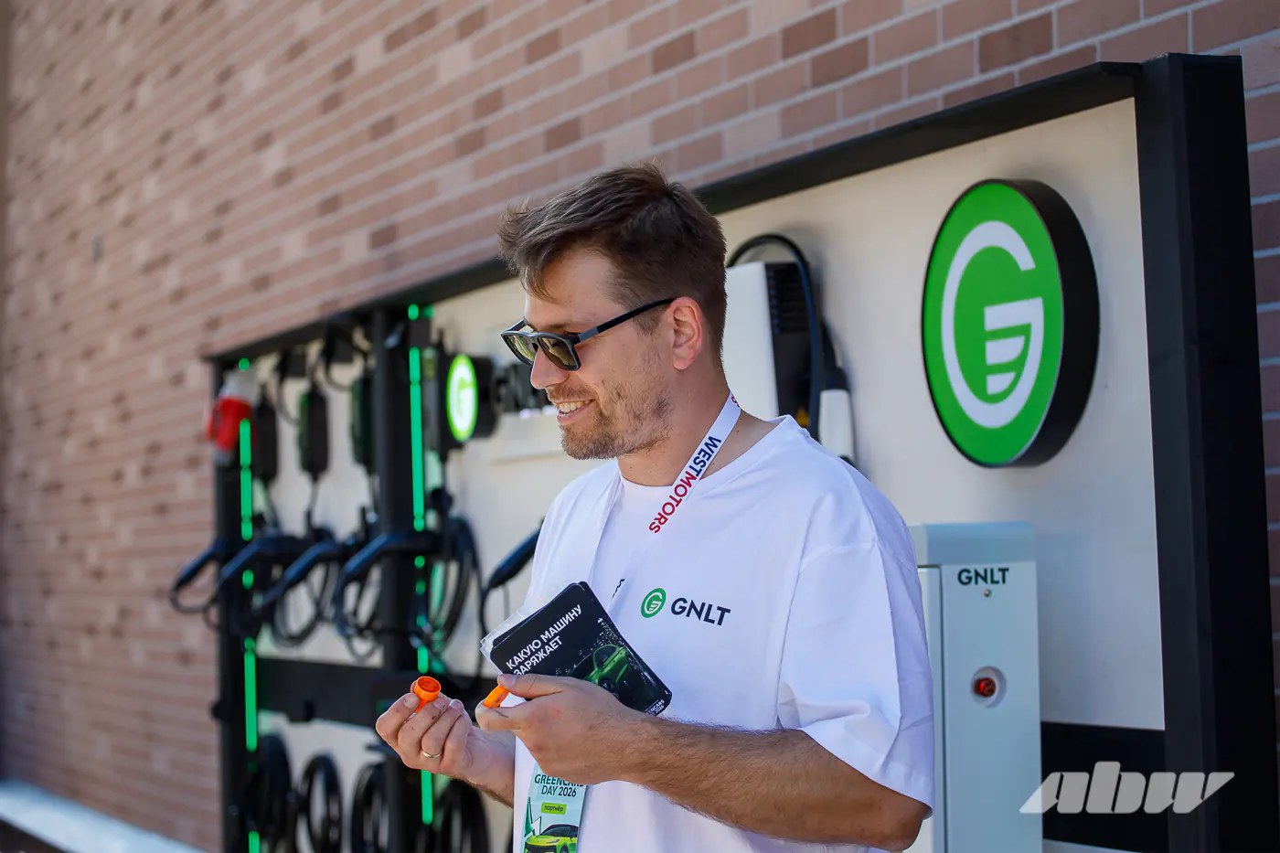 Посетитель Green Cars Day 2026 с зарядным устройством GNLT у стенда